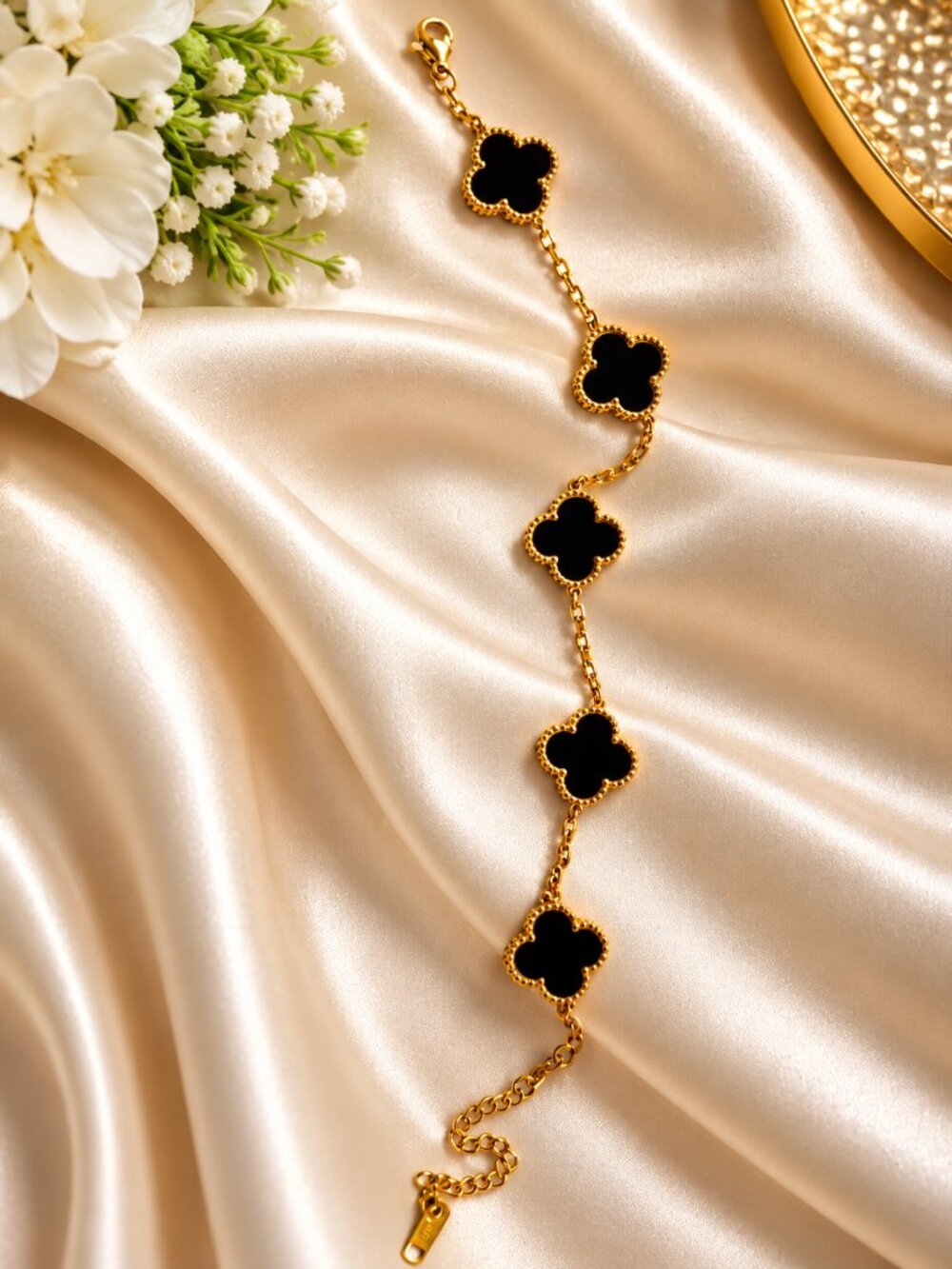 Gold-tone bracelet featuring five green four-leaf clover black charms with beaut